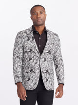 Man wearing a patterned blazer over a black shirt on a white background