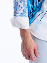 Close-up of a person wearing a white shirt with blue and black patterned sleeves on a white background