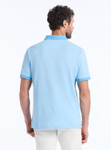 Man wearing a light blue polo shirt with a white background