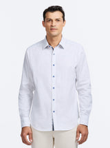 Man wearing a light blue patterned shirt against a white background