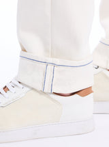 Close-up of a white sneaker with blue stitching on a white background