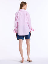 Woman wearing a pink blouse and denim shorts on a white background