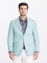 Man wearing a light blue blazer over a patterned shirt on a white background