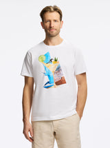 Man wearing a white t-shirt with a colorful drink and beach graphic design on a white background