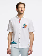 Man wearing a white short-sleeve shirt with colorful designs on a white background