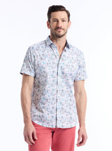 Man wearing a patterned short-sleeve shirt and pink pants on a white background