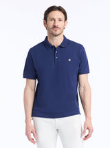 Man wearing a blue polo shirt with a small devil logo on a white background
